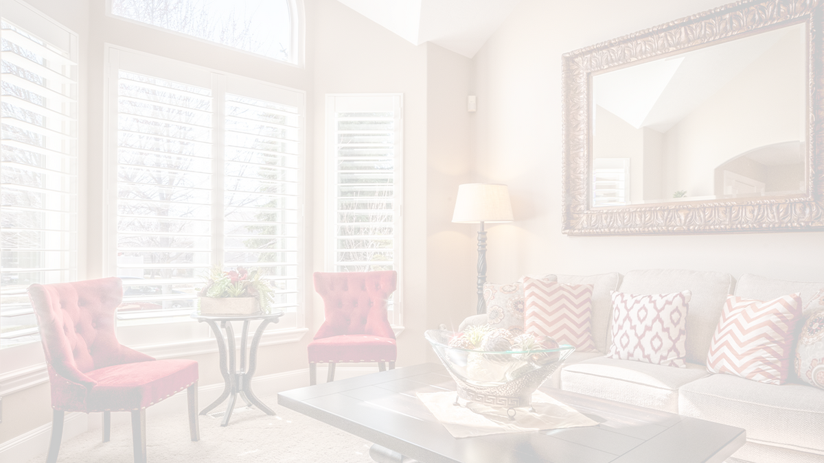 whitened image of a living room with a big ornate mirror hung above the couch