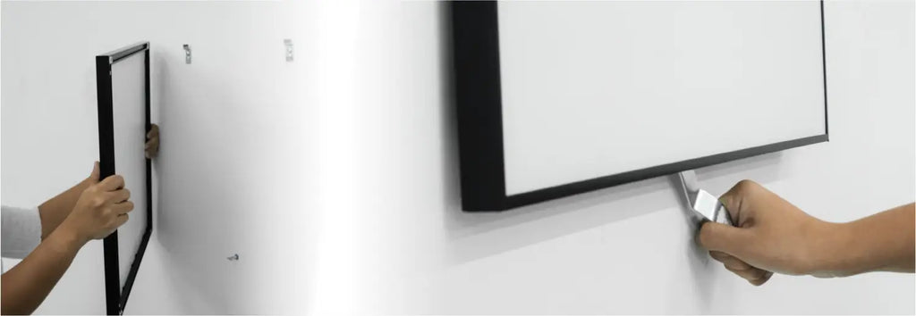 Left image shows hands hanging a metal frame on the wall using the mounting plates and wall brackets. Right image shows a hand rotating the T-head screw at the back of the frame using a security wrench.