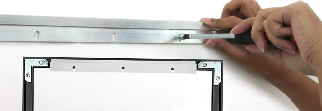 Hands mounting metal cleats to the wall using a screwdriver