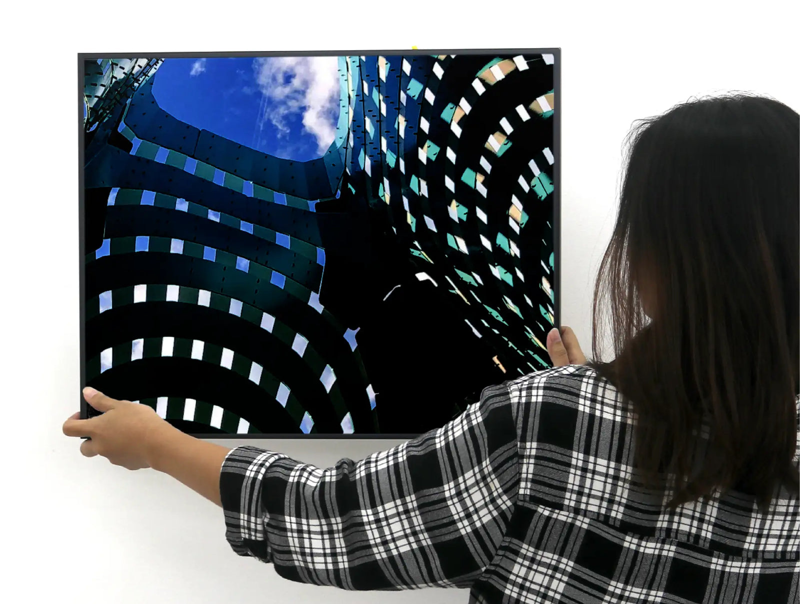 Black-framed television displaying a vibrant architectural image with blue sky and geometric patterns.