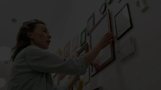 A woman hanging a picture on a gallery wall