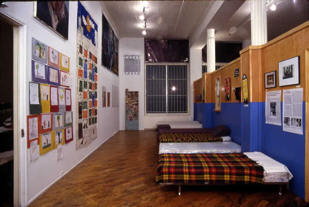 A cramped room with several prints on all walls