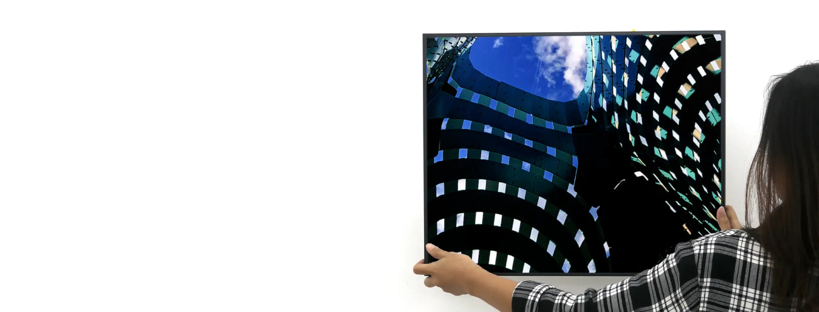 A sleek black-framed television displaying a vibrant cityscape with blue sky and geometric building patterns.